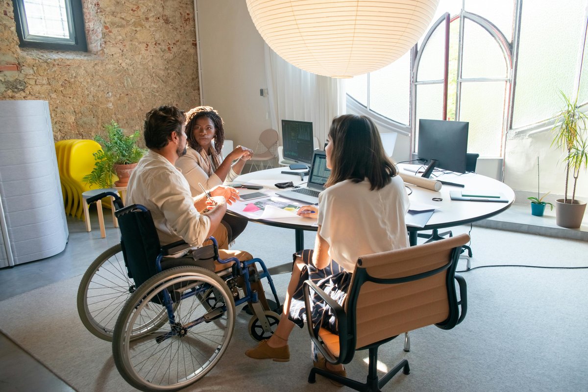 Diverse NDIS provider team collaborating in an accessible, inclusive office environment